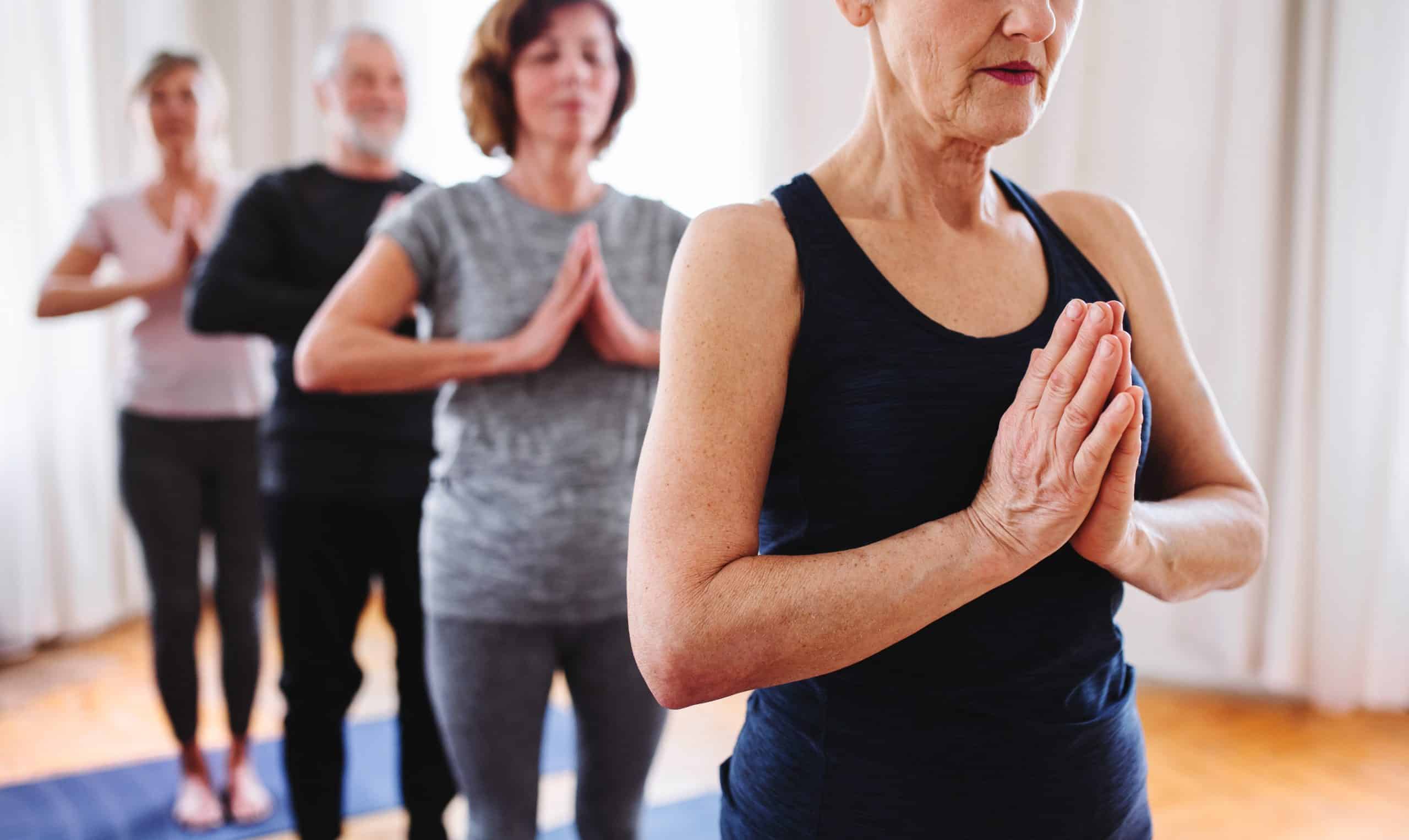 Group of senior people doing yoga exercise in community center club. yoga adapté