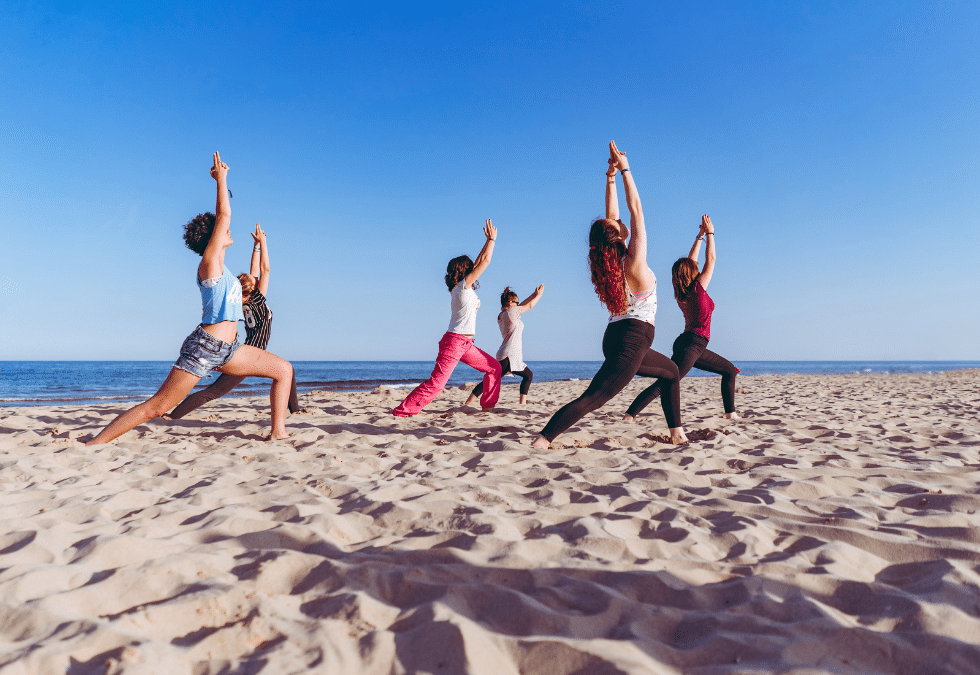 groupe de 6 personnes qui font du yoga sur la plage